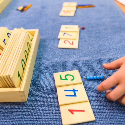 Hands of a student boy using wooden material in a Montessori school.